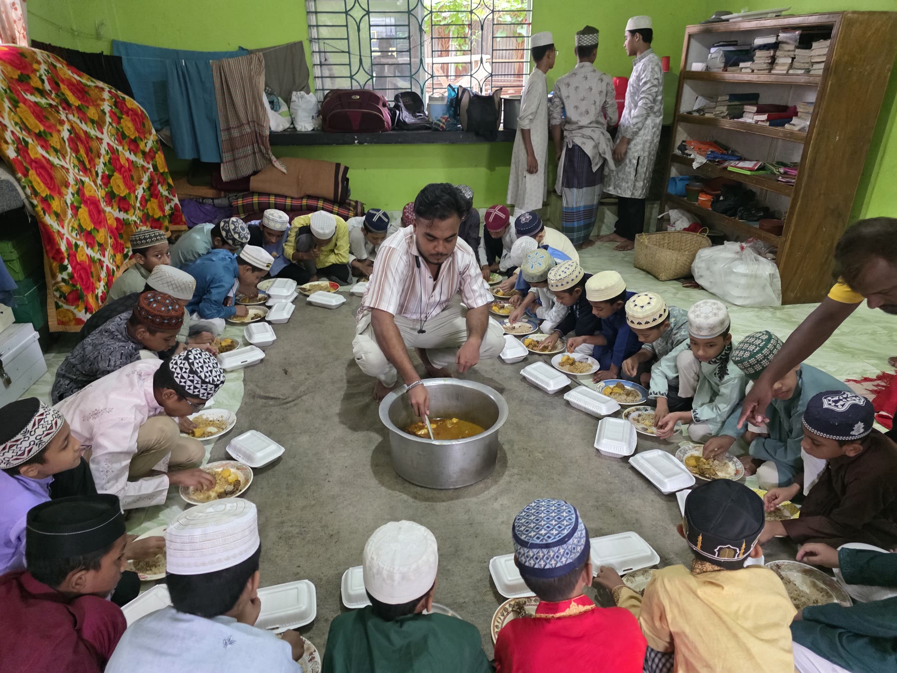 Orphan students at a madrasa share a meal provided through Case 004.
